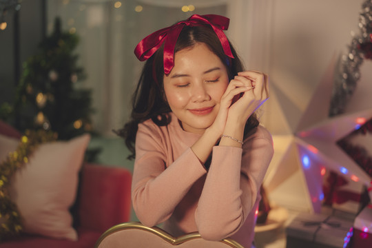 在圣诞派对上，一位年轻的亚洲女子留着黑色的头发，戴着阅读丝带。