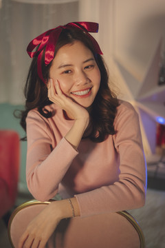在圣诞派对上，一位年轻的亚洲女子留着黑色的头发，戴着阅读丝带。