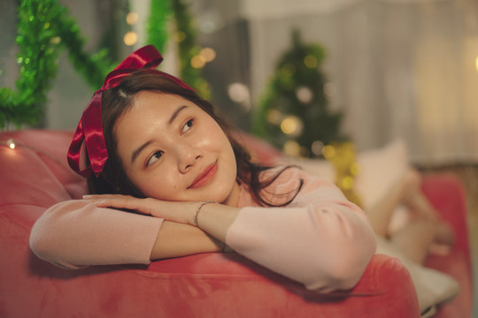 美丽年轻的亚洲女性黑色头发，红色丝带头带躺在沙发上。