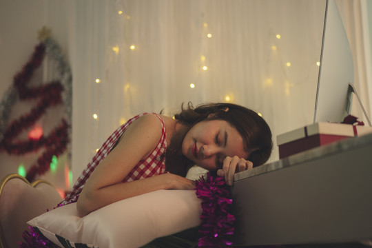 美丽的亚洲年轻女子黑发睡在电脑前，圣诞派对后在线庆祝。