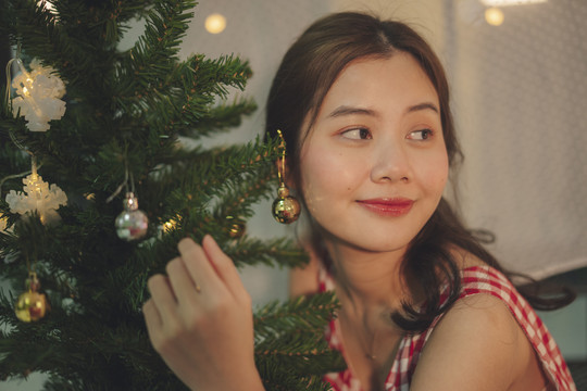 美丽的亚洲年轻女子黑头发在派对上装饰圣诞树。