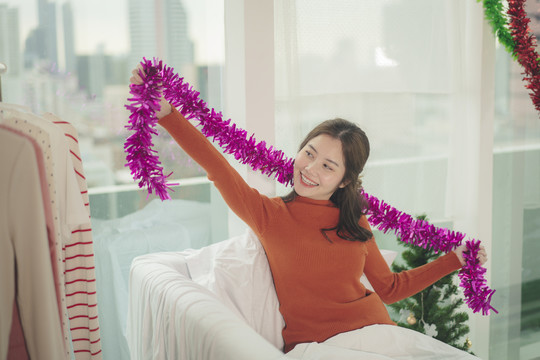 美丽的亚洲年轻女子黑头发在家玩圣诞装饰品。