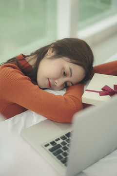 美丽的亚洲年轻女子在圣诞节睡在笔记本电脑前的黑发。