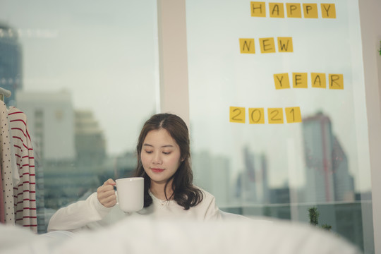 美丽的亚洲年轻女子在圣诞节拿着一杯咖啡，头发乌黑。