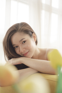 年轻亚洲美女躺在沙发上的特写照片。护肤美容产品概念。