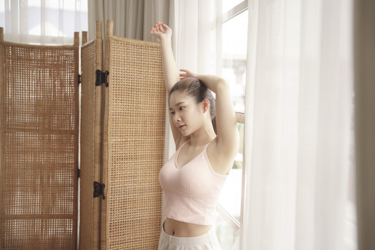 年轻的亚洲美女在家里练习瑜伽前要热身。