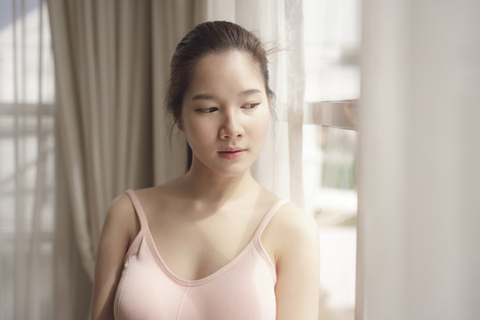 白色房间里穿着粉红色衬衫的年轻亚洲美女肖像。护肤治疗理念。