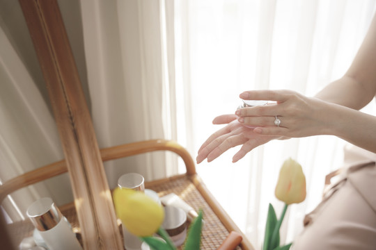 在起居室的化妆台上，一名妇女正在用护肤液罐洗手。