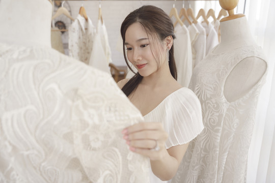 亚洲新娘选择婚礼礼服的美丽肖像。