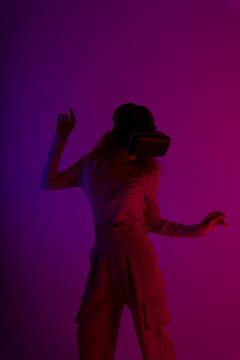快乐女人在霓虹灯背景下佩戴虚拟现实VR护目镜。