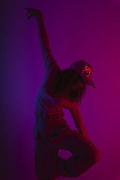 在黑暗霓虹灯背景下跳舞的年轻时髦女人的肖像。