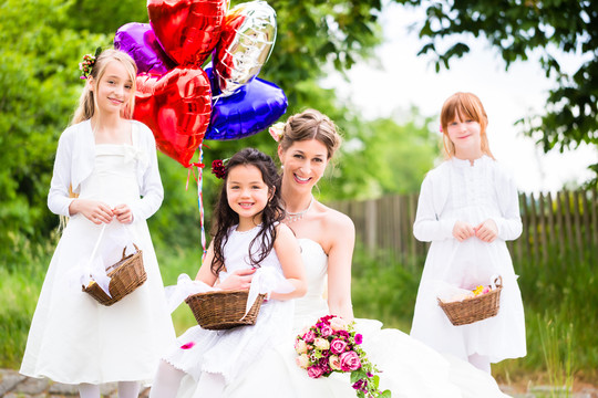 新婚夫妇带着花儿的新娘或穿着白色礼服和花篮的伴娘