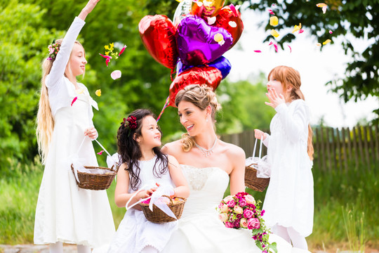 新婚夫妇新娘和新郎，带着花儿或伴娘，穿着白色礼服和花篮