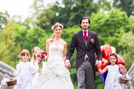 新婚夫妇新娘和新郎，带着花儿或伴娘，穿着白色礼服和花篮