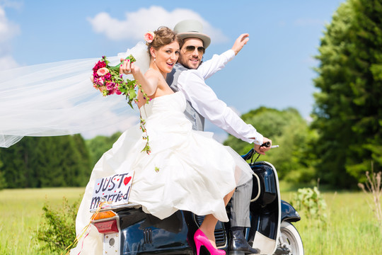 婚礼新郎和新娘驾驶摩托车玩得很开心，贴上了新婚标志