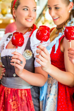 朋友们穿着民族服装一起参观巴伐利亚博览会，吃着苹果糖