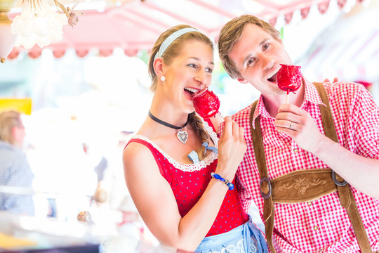 穿着民族服装的情侣们一起参观巴伐利亚博览会，吃着苹果糖