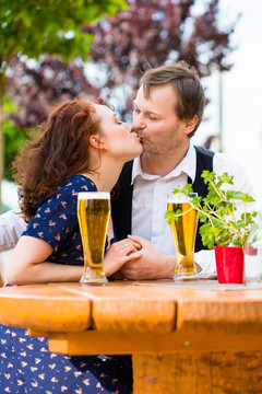一对情侣在啤酒花园里畅饮，亲吻爱情