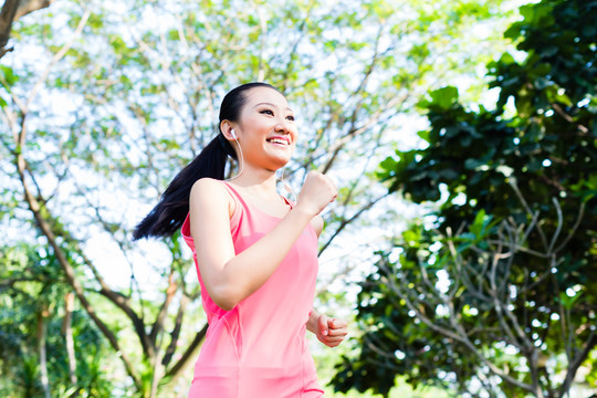 亚洲女子跑步者在城市公园慢跑