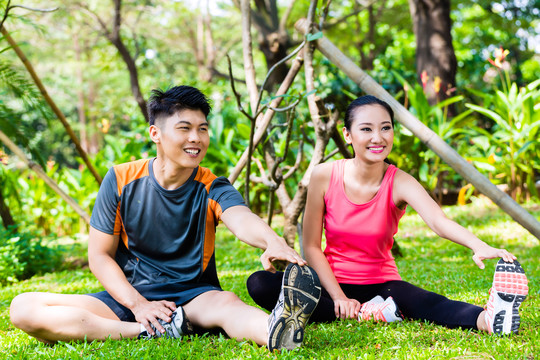 亚洲华人男子和女子在公园伸展肌肉进行运动健身