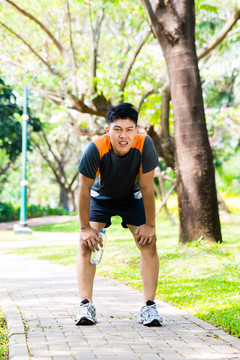 一名亚洲男子在城市公园慢跑后上气不接下气