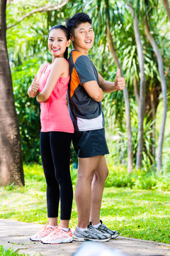 亚洲华人男女在城市公园健身慢跑后休息