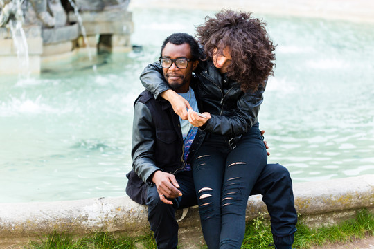 城市里的一对非洲夫妇坐在喷泉旁