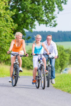 父母和女儿在乡间小路上骑自行车或骑自行车旅游
