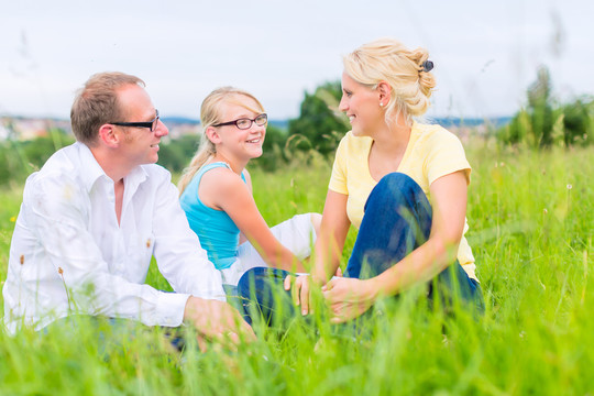 父母和女儿坐在草地或田野上