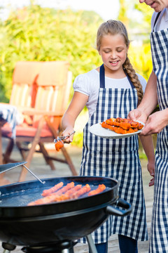 一家父女在家庭花园烧烤时吐烤肉