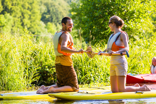 女人和男人站在河上用桨板支撑