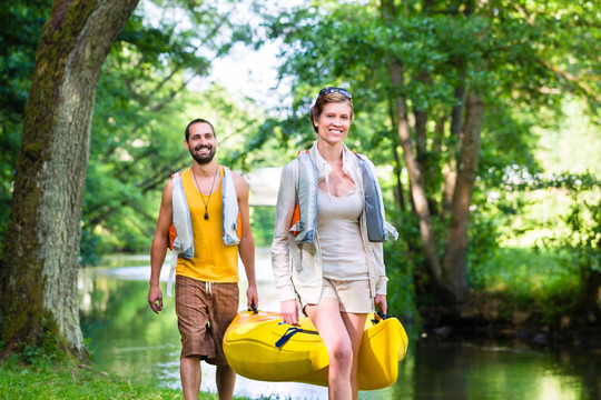 男子和妇女携带独木舟到森林河