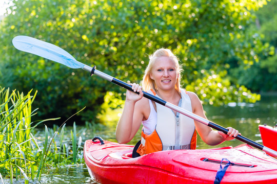 在森林河上划皮艇或独木舟的妇女