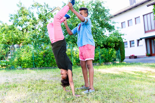 兄弟姐妹，两个黑人孩子，在花园里玩倒立