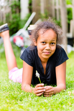 夏天，一个带着草叶躺在草地上的黑女孩