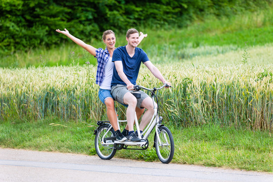 男人和女人，一对夫妇，在乡间小路上一起骑双人自行车