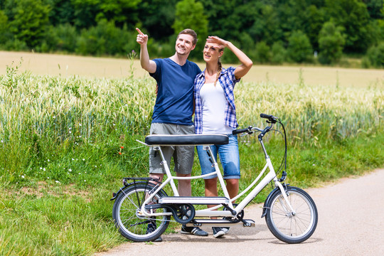 男人和女人，一对夫妇，在乡间小路上一起骑双人自行车
