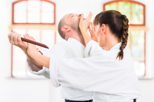 在武术学校合气道训练中，一男一女拿着木刀打架