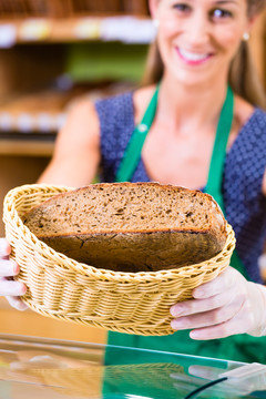 有机超市面包店的女面包师为顾客提供面包