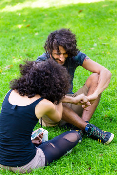 夏日坐在草地上聊天的拉丁时髦夫妇