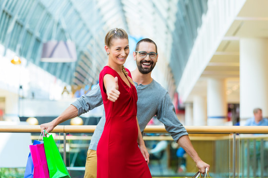一对夫妇，男人和女人，在现代购物中心带着包