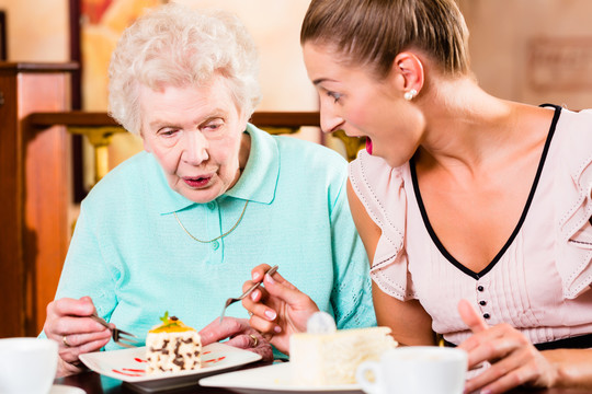 老太太和孙女在咖啡馆喝咖啡吃蛋糕
