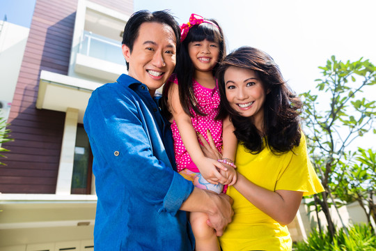 亚洲华人家庭的父母和孩子骄傲地站在现代家庭的前面