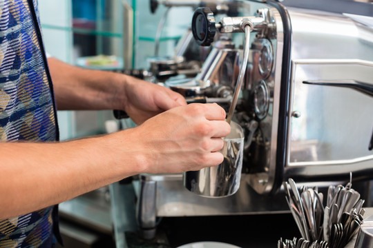 咖啡馆或咖啡吧的咖啡师准备合适的卡布奇诺，将牛奶泡沫倒在杯子里