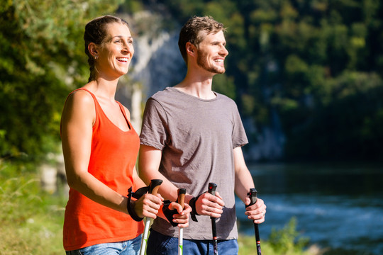 男子和女子夏季在河边徒步旅行，以增强体质