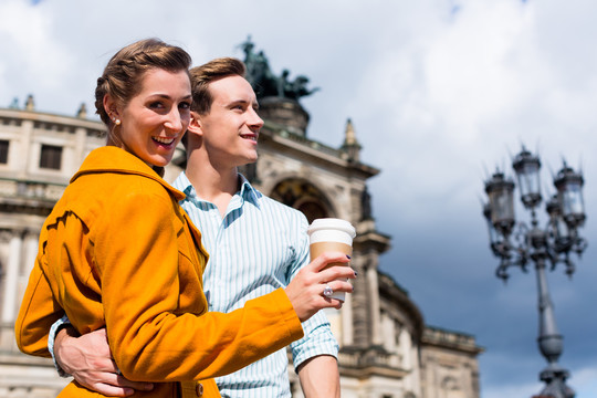 德累斯顿Semperoper的一对旅游夫妇带着咖啡散步，准备外卖