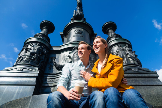 一对旅游夫妇坐在德累斯顿剧院广场雕像前