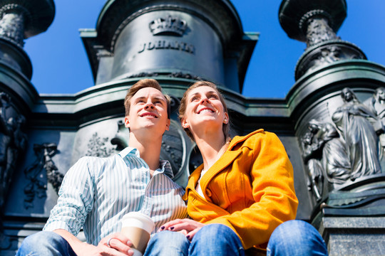 一对旅游夫妇坐在德累斯顿剧院广场雕像前