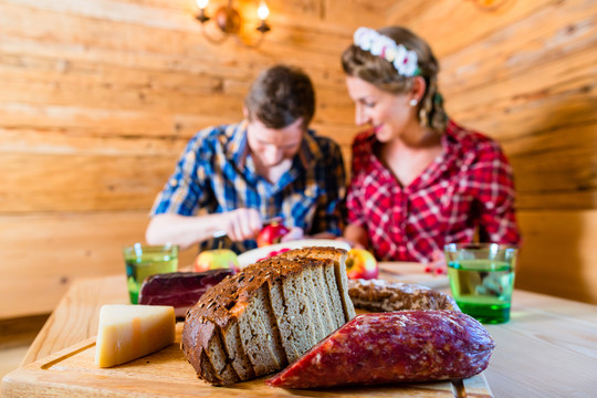 这对夫妇在山上的小屋里吃午餐，吃面包和冷盘