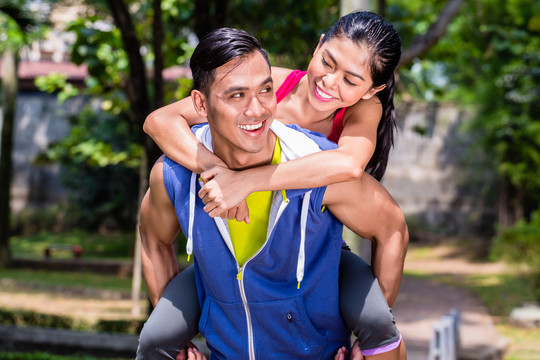 一名亚洲男子在运动训练期间休息时背着女友进行运动